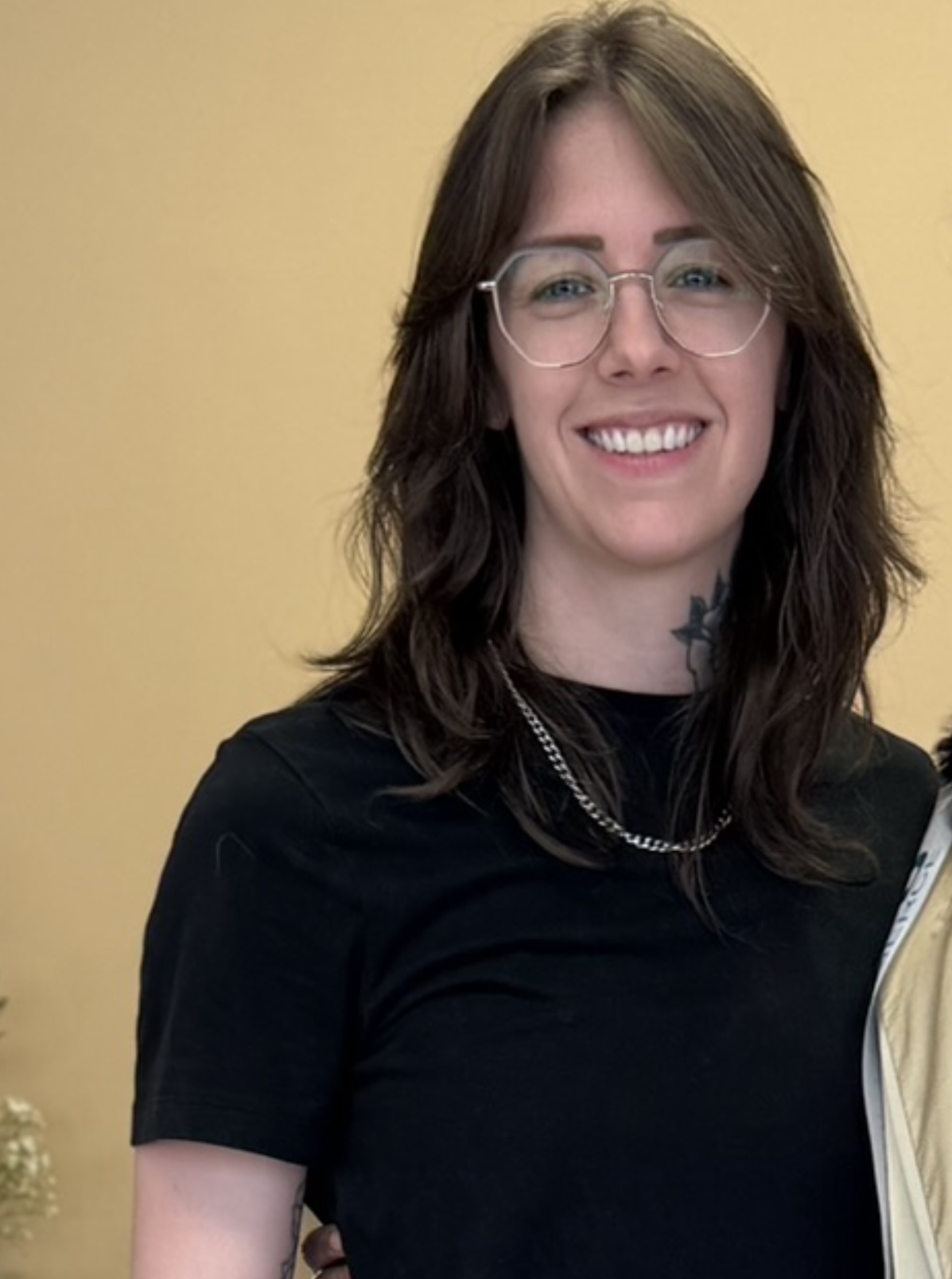 Devon smiles into the camera in front of a plain wall.