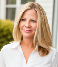 Amy Sousa headshot - she wears a white button-down shirt and stands in front of a white building with a window