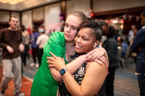 An adult resident hugs a staff member