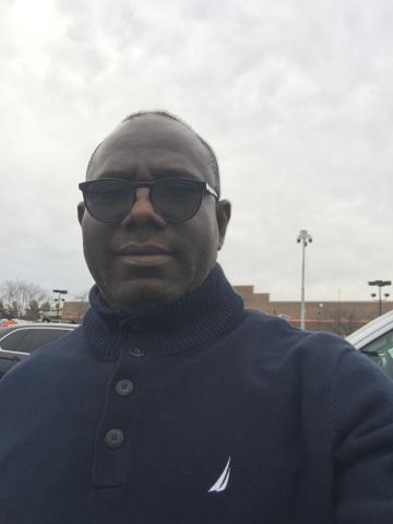 Tunde Bamigboye looks into the camera with a neutral expression. He is wearing sunglasses on a bright, cloudy day.